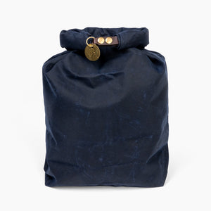 Closed large navy blue waxed canvas roll top stuff sack with leather closure and brass tag 