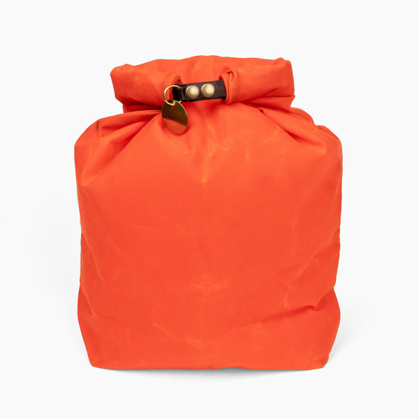 Closed large hunter orange waxed canvas roll top stuff sack with leather closure and brass tag 