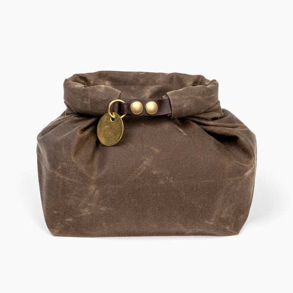 Closed medium forest brown waxed canvas roll top stuff sack with leather closure and brass tag 