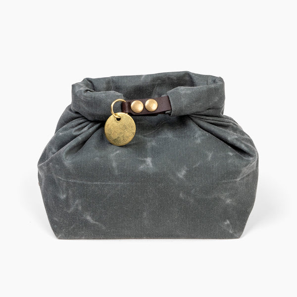 Closed medium slate gray waxed canvas roll top stuff sack with leather closure and brass tag 