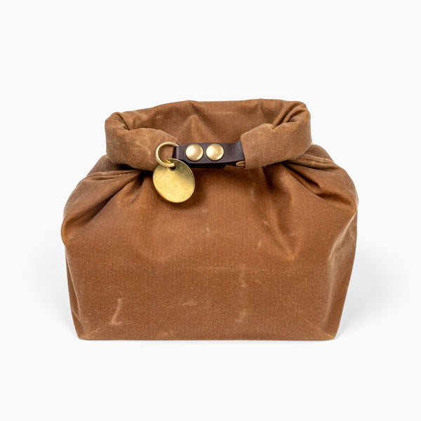 Closed medium golden honey waxed canvas roll top stuff sack with leather closure and brass tag 