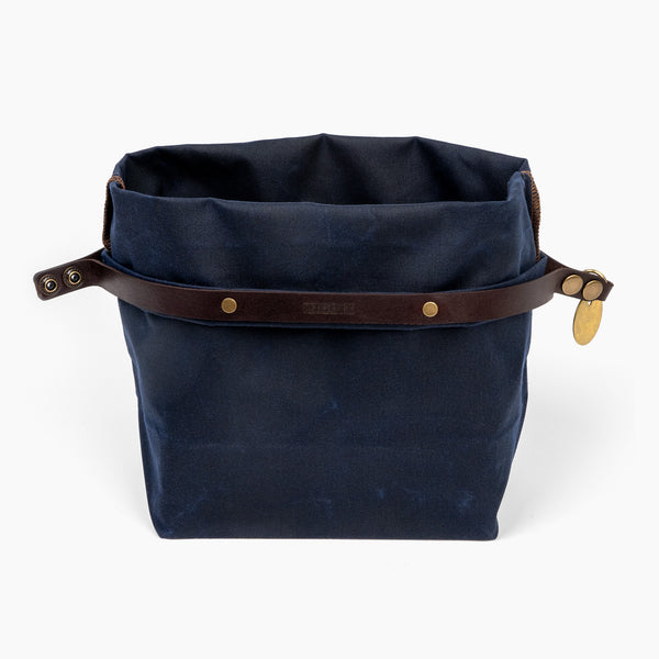 Open medium navy blue waxed canvas roll top stuff sack with leather closure and brass tag 