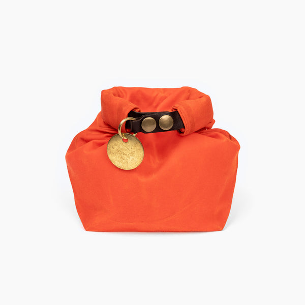 Closed Small Hunter Orange waxed canvas roll top stuff sack with leather closure and brass tag 