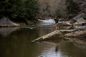 Casting a handline from a rock at the edge of a stream