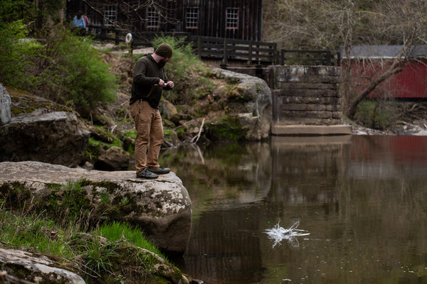 Man handline fishing from a rock catching a trout